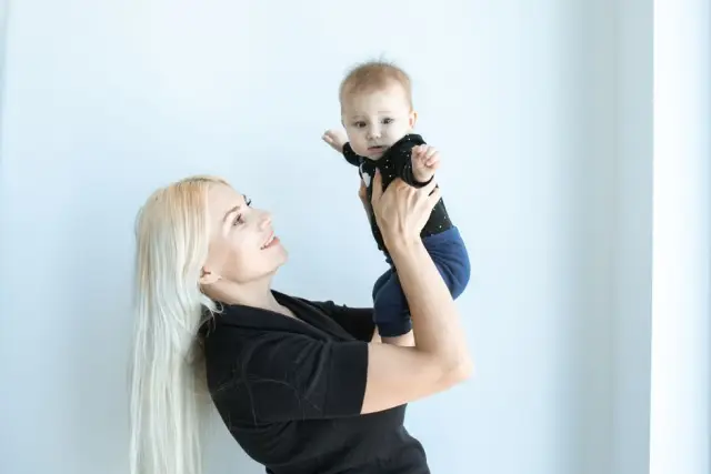 Mãe loira sorrindo com o bebê recém-nascido