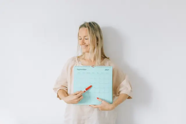 Mulher loira sorrindo apontando o calendário