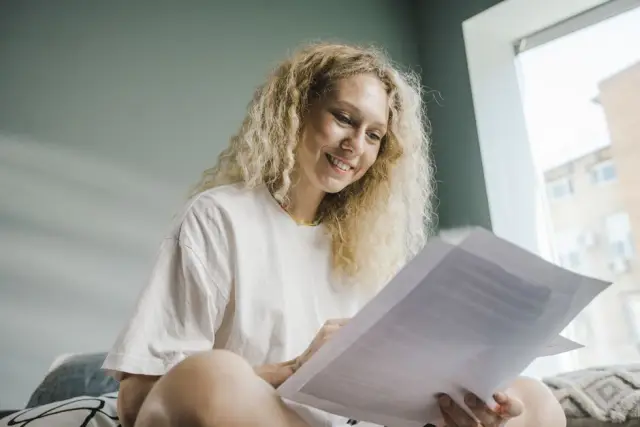 Mulher loira sorrindo lendo o contrato do plano